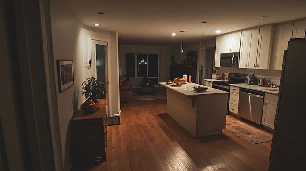 Modern kitchen with wood flooring, island, and cozy seating, illuminated by warm lighting.