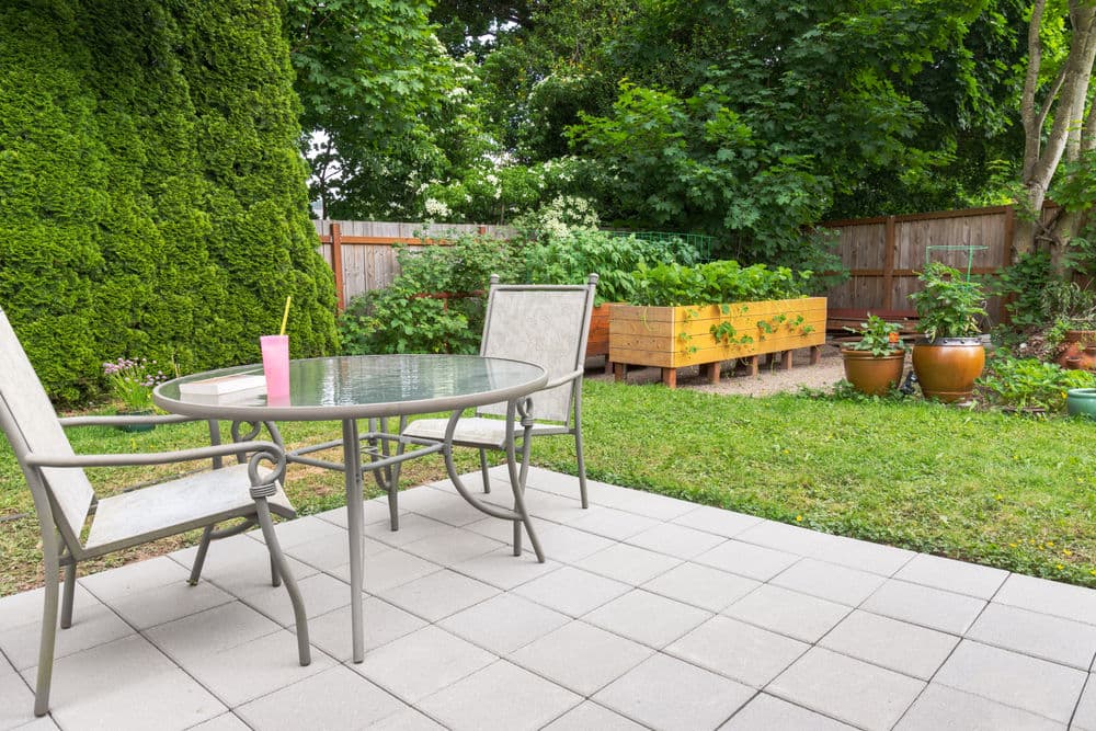 Patio with table and chairs overlooking a vibrant garden and greenery. Ideal outdoor space.
